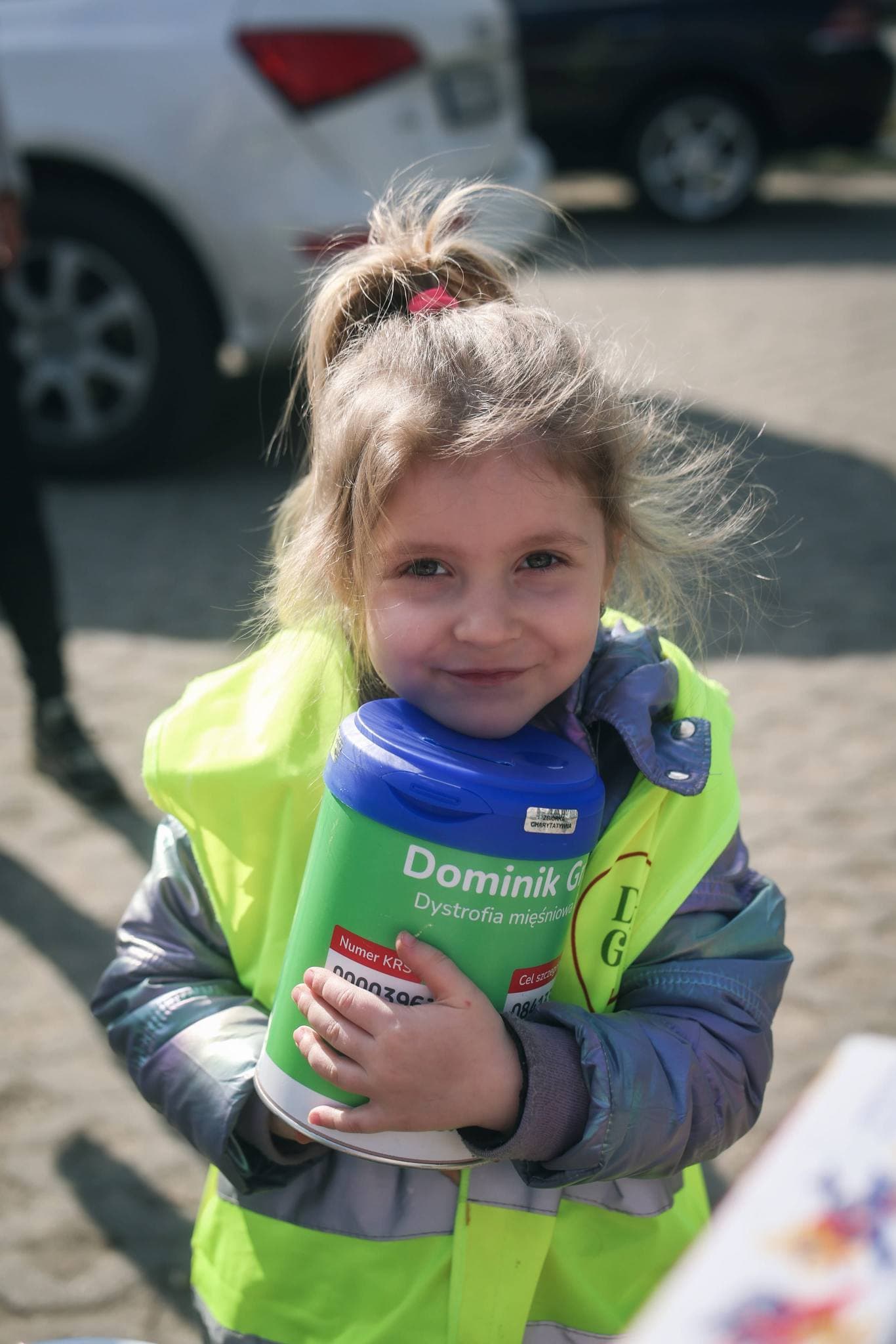 Milenka, siostra Dominika, trzyma puszkę na zbiórkę dla Dominika podczas kiermaszu